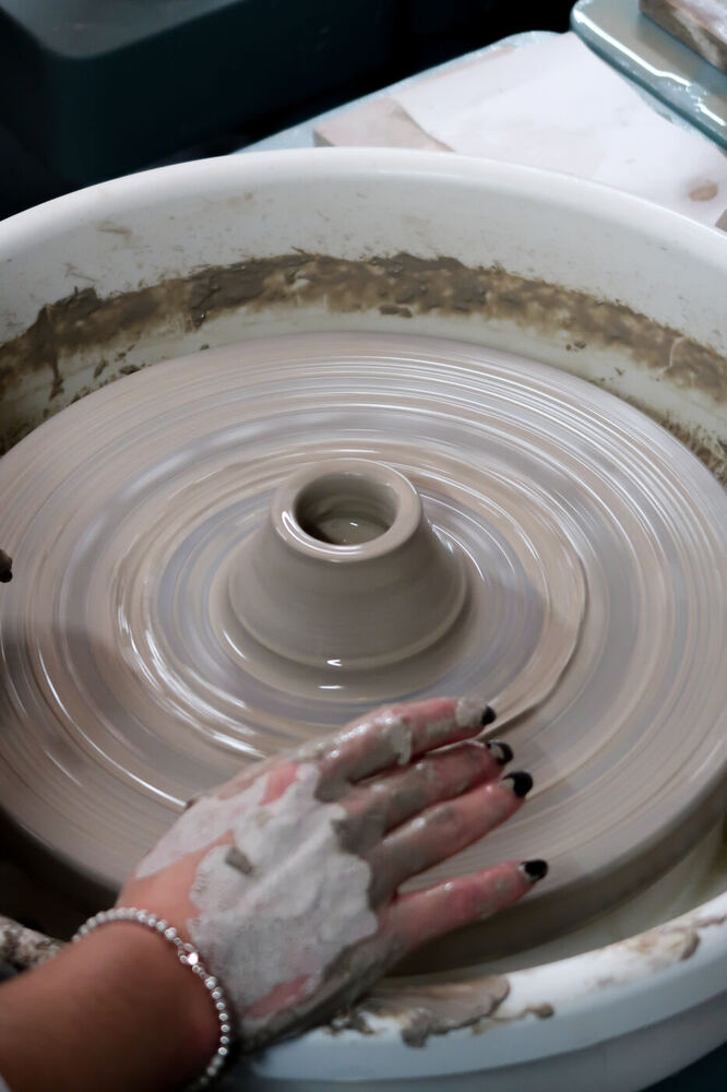 Hands shaping clay on the wheel